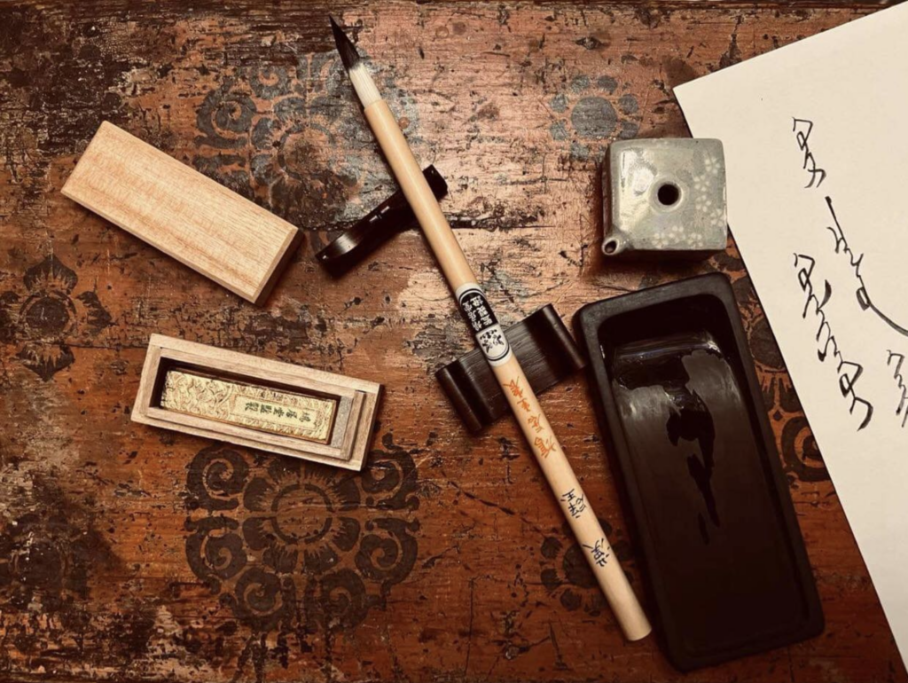 This photograph is of Mongolian Khalkha Zava Damdin’s (1976- ) calligraphy ink brush and tools on his traditional Mongolian table. In English, the Mongol Bichig script (on the right, "ХҮЛЭЭХҮЙ") translates as “Waiting.” Location: Soyombot Oron, Delgertsogt Sum in the Gobi Desert of Mongolia. 21 February 2024. Photograph: Reprinted on CPinMongolia.com with permission.